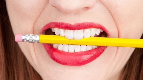 Frau hat einen Bleistift zwischen den Zähne - Foto: iStock/sdominick