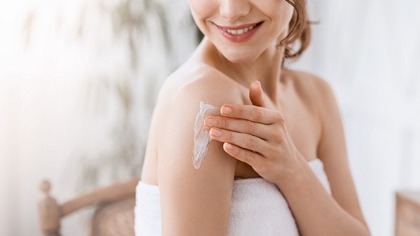 Eine Frau cremt sich nach dem Duschen mit Bodylotion ein - Foto: iStock_Prostock-Studio