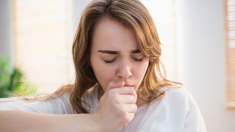 Eine Frau hält sich die Hand vor den Mund und hustet - Foto: iStock/Wavebreakmedia