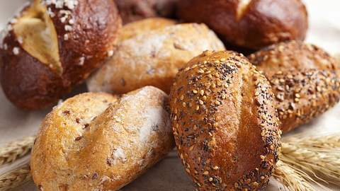 Verschiedene Brötchen auf einem Tuch, darunter einige Ähren - Foto: iStock/OlgaMiltsova 