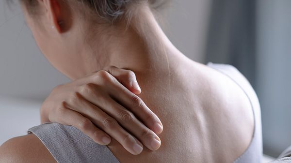 Eine Frau hält ihre Hand an ihren schmerzenden Rücken - Foto: iStock/amenic181