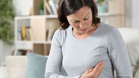 Frau in den Wechseljahren greift sich an die schmerzende Brust - Foto: iStock/Pheelings Media
