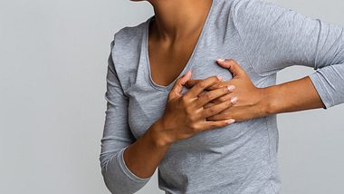 Junge Frau hält sich die schmerzende Brust - Foto: iStock/prostock-studio