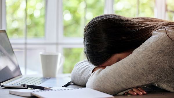 Frau mit Burnout liegt mit dem Kopf auf einem Schreibtisch - Foto: iStock/PeopleImages