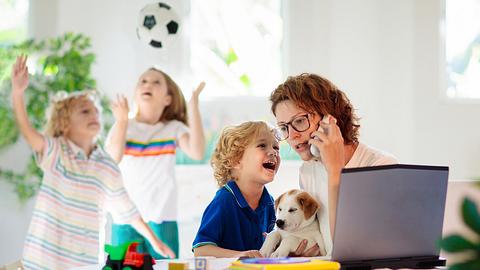 Mutter sitzt am Laptop und telefoniert, drei Kinder toben um sie herum - Foto: iStock/FamVeld