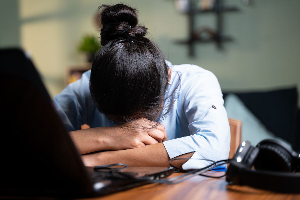 Frau mit Burnout legt ihren Kopf auf dem Schreibtisch ab