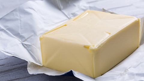 Ein Stück Butter in der offenen Verpackung - Foto: iStock/orinoco-art