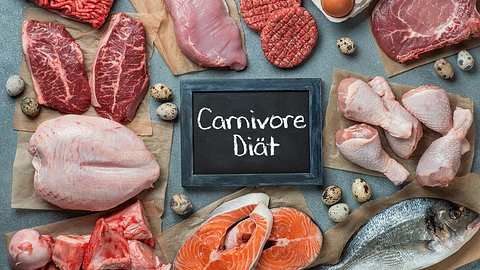 Verschiedene Fleischsorten auf einem Tisch, mit einem Schild, auf dem Carnivore Diät steht - Foto: istock_Fascinadora