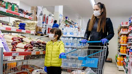 Frau trägt Einweghandschuhe beim Einkaufen. - Foto: iStock / Phynart Studio
