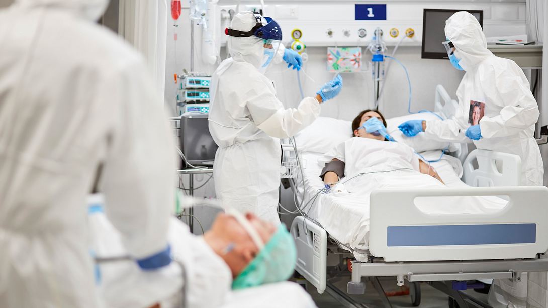 Ärzte in Schutzkleidung und Patienten in Betten - Foto: iStock/Morsa Images