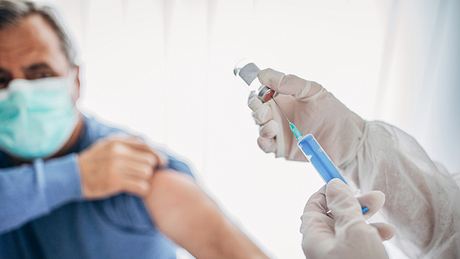 Mann kriegt Corona-Impfstoff mit Spritze verabreicht - Foto: iStock / South_agency