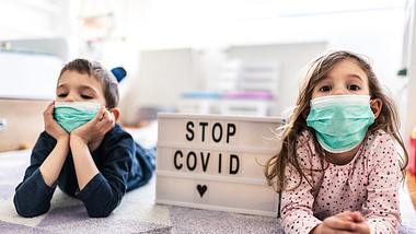 Kinder tragen Mundschutz zu Hause - Foto: iStock / SanyaSM
