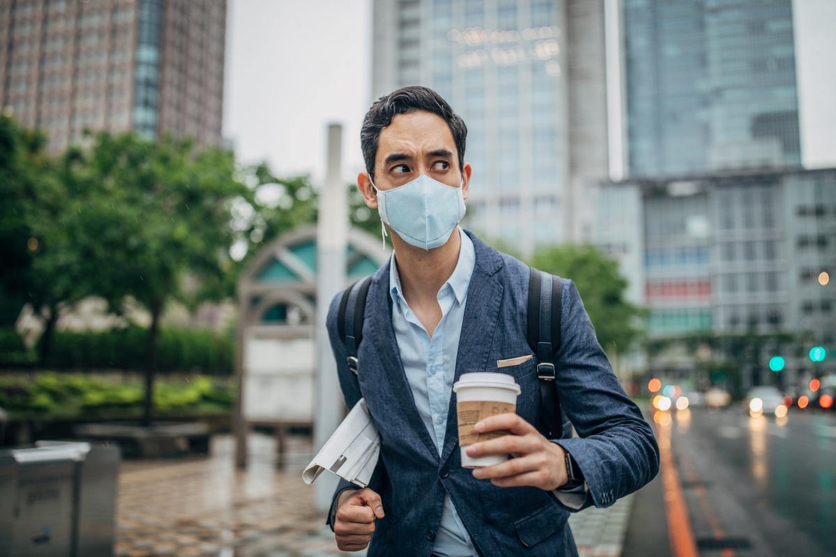 Mann mit Atemschutzmaske in Großstadt