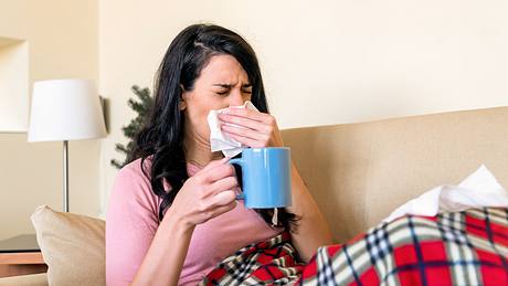 Frau mit Corona-Symptomen schnäubt sich die Nase - Foto: iStock/RealPeopleGroup