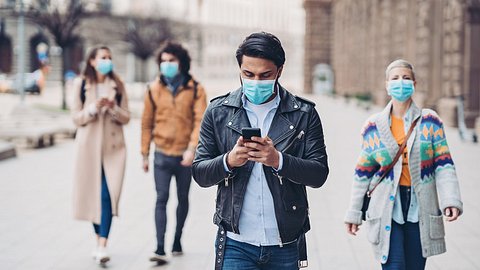 Menschen gehen mit medizinischen Masken durch die Straßen - Foto: istock/pixelfit