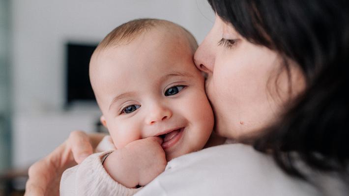 Eine Frau küsst ihr lachendes Babys auf die Wange - Foto: iStock_erreperdomo