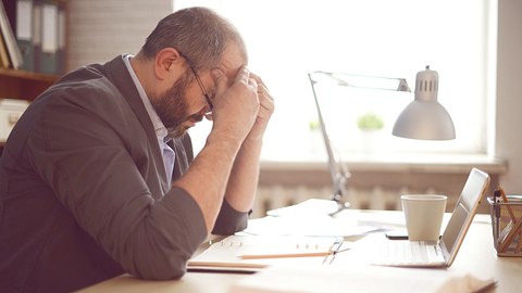 Mann ist erschöpft am Schreibtisch - Foto: iStock/elenaleonova