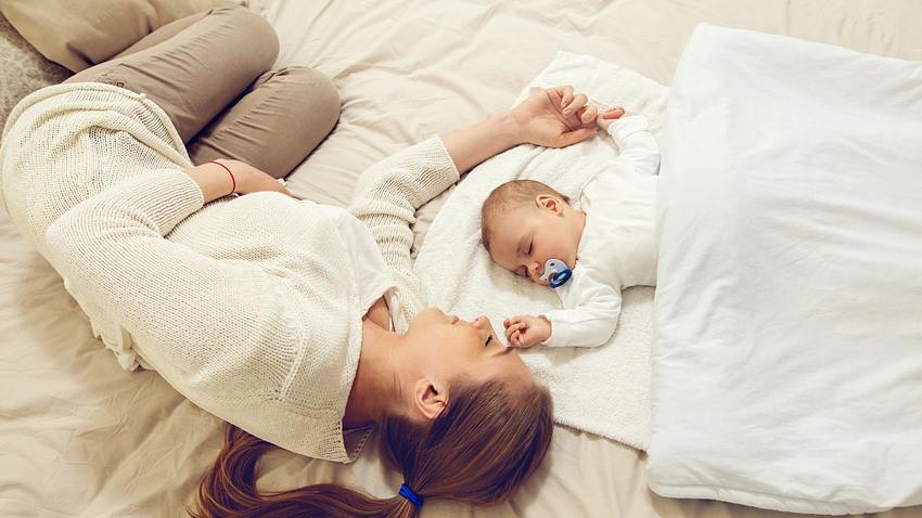 Frau schläft mit Baby im Bett - Foto: iStock/skynesher