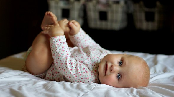 Baby mit Füßen in der Hand - Foto: iStock/christinlola