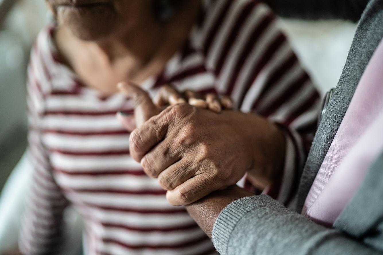 Pflegerin hält die Hand einer älteren Frau