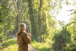 Frau mit Jacke steht im Wald - Foto: iStock/AscentXmedia