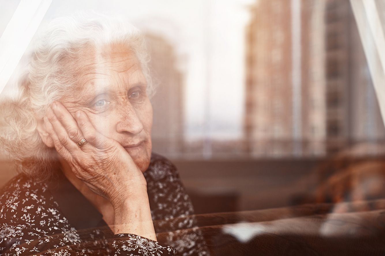 Alte Frau mit Demenz schaut aus dem Fenster