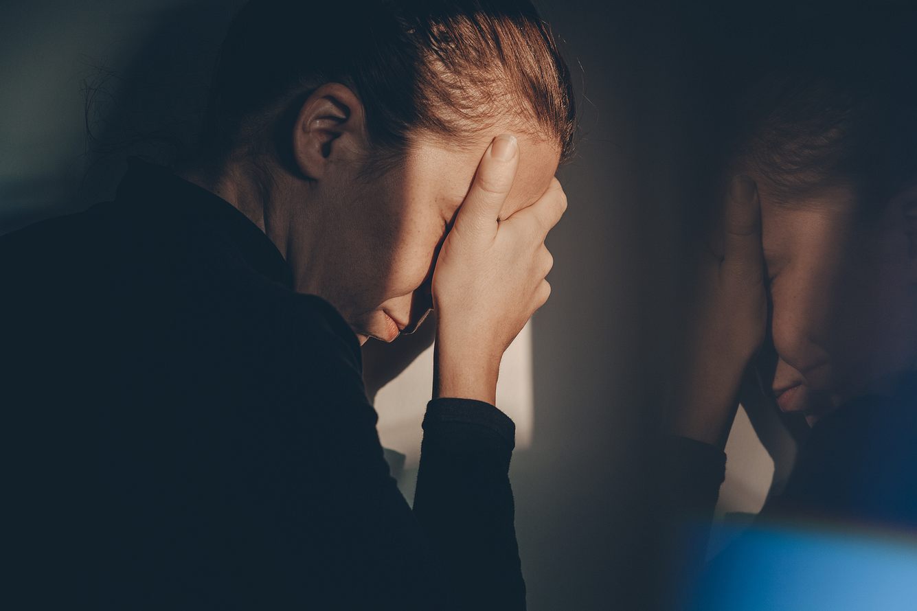 depression-nach-trennung EIne Frau vergräbt ihr Gesicht in ihrer Hand