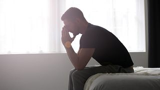 Mann hat depressive Symptome und sitzt auf der Bettkante - Foto: iStock/glegorly