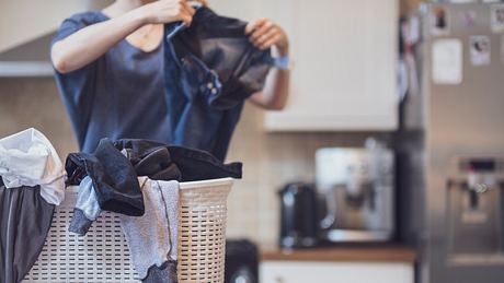 Eine Frau legt Wäsche in die Waschmaschine - Foto: iStock/EllenMoran