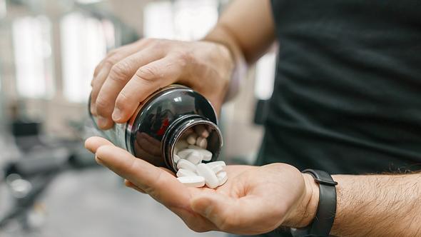 Ein Mann schüttet sich Tabletten in die Hand  - Foto: iStock/Valeriy_G