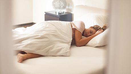 Eine Frau liegt im Bett und schläft - Foto: iStock/gruizza