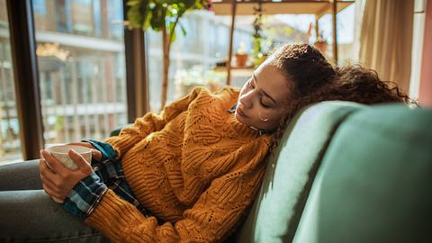 Eine Frau sitzt müde auf dem Sofa - Foto: iStock/DaniloAndjus