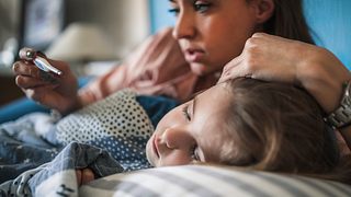 Kind liegt krank im Bett, Mutter misst Fieber - Foto: iStock-1216399995 zeljkosantrac