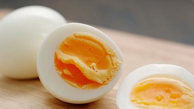 Ein ganzes und ein aufgeschnittenes gekochtes Ei auf einem Holzbrett - Foto: iStock john shepherd
