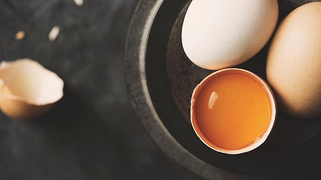 Ein aufgeschlagenes Ei liegt neben zwei Eiern - Foto: istock/TARIK KIZILKAYA