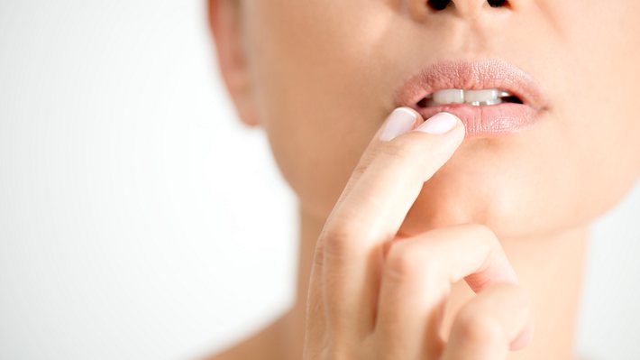 Eine Frau fasst sich an den Mund - Foto: iStock/simarik