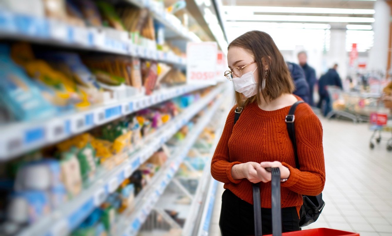Frau mit Mundschutz steht im Supermarkt