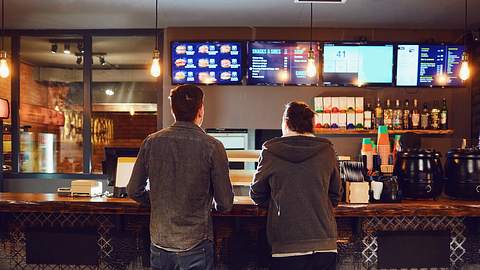 Zwei Personen stehen an der Theke in einem Fastfood-Restaurant - Foto: Istock/Lacheev