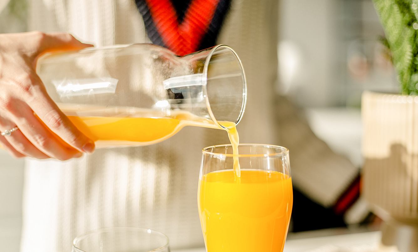 Ein Mann gießt Orangensaft in ein Glas