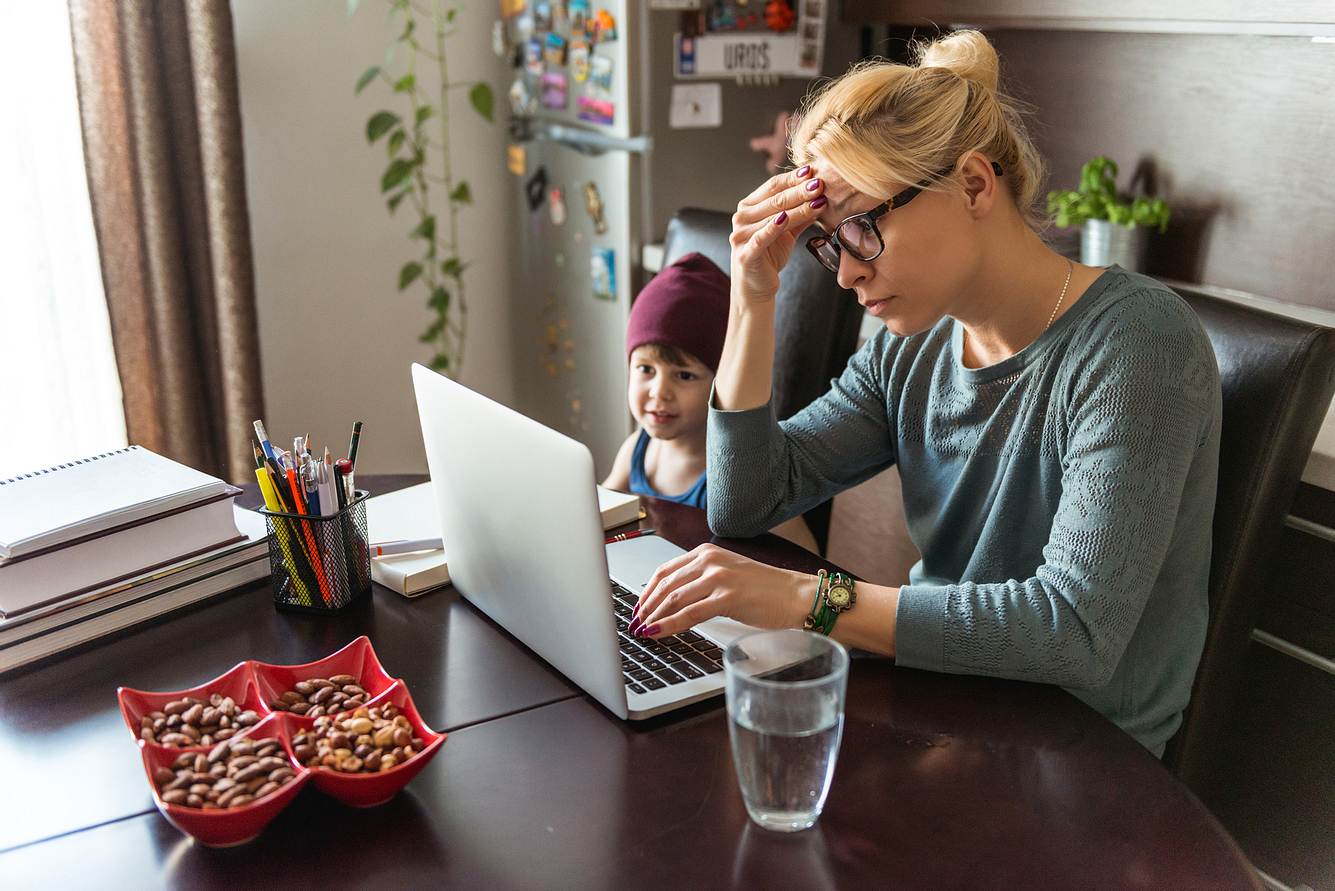 emotionaler-stress Frau sitzt angespannt vor dem Laptop und fasst sich an die Stirn