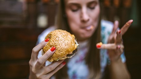 Eine Frau isst einen Burger - Foto: istock_miodrag ignjatovic