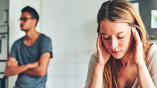 Frau hält sich die Ohren zu, Mann steht im Hintergrund - Foto: iStock/Charday Penn