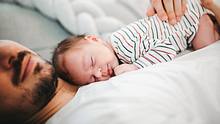 Vater hält Baby im Arm - Foto: iStock/Nikola Stojadinovic