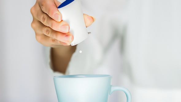 Frau macht Süßstoff in Tasse - Foto:  iStock/bluecinema