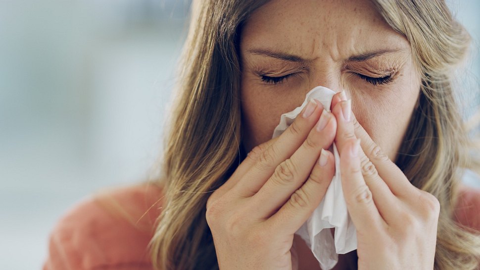 Eine erkältete Frau schnäuzt ihre Nase - Foto: iStock_Cecilie_Arcurs