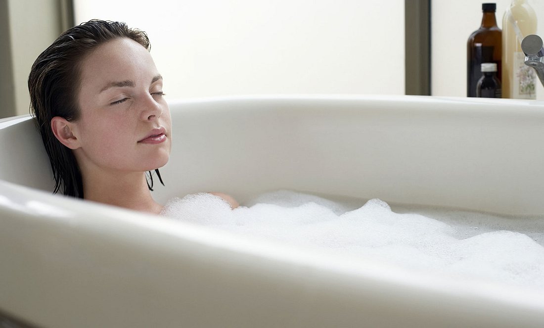 Eine Frau liegt mit geschlossenen Augen in einer Badewanne
