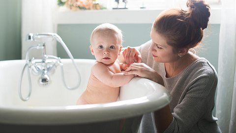 Junge Frau badet ihr Baby - Foto: istock/manonallard_1