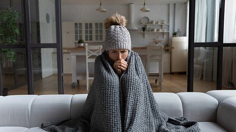 Frau sitzt in der kalten Wohnung - Foto: iStock/fizkes