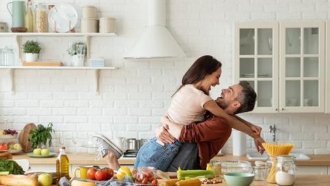Verliebtes Paar beim Kochen in der Küche, auf dem Tisch Gemüse - Foto: iStock-1222190359 deniskomarov