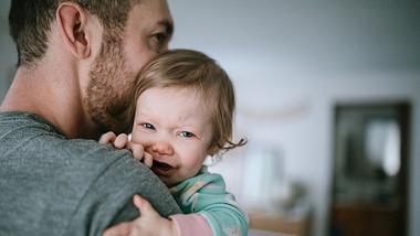 Krankes, weinendes Kind auf dem Arm des Vaters - Foto: istock/﻿RyanJLane